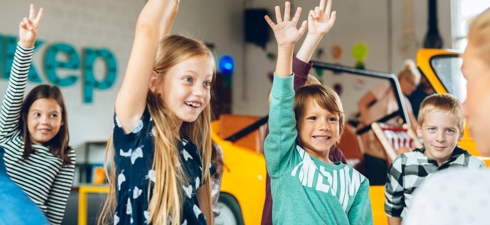 kids raising their hands in a classroom